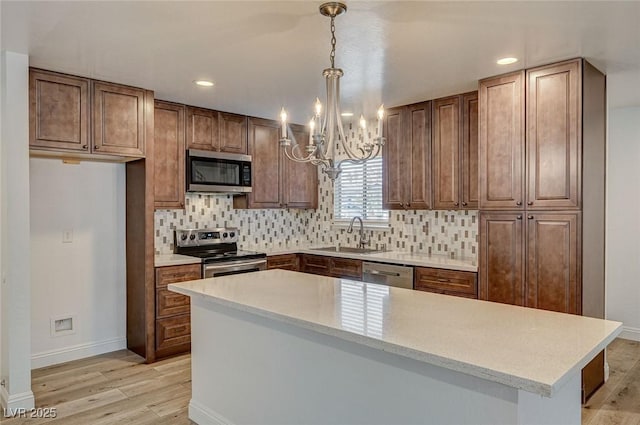 kitchen featuring sink, stainless steel appliances, light hardwood / wood-style flooring, backsplash, and pendant lighting