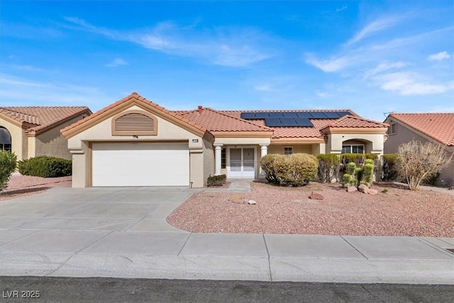 mediterranean / spanish-style house featuring a garage and solar panels