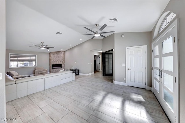 unfurnished living room featuring a fireplace, ceiling fan, and lofted ceiling