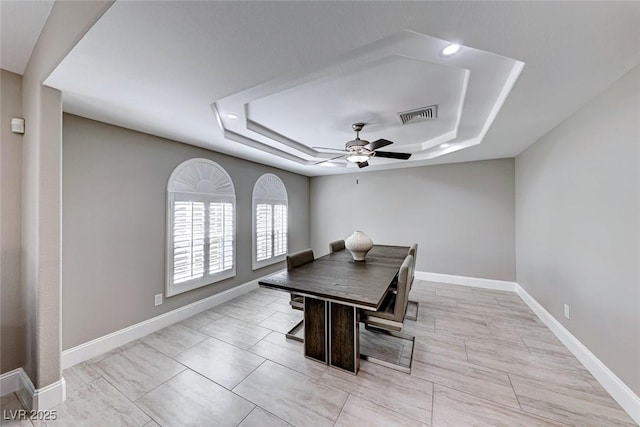 dining room with ceiling fan and a raised ceiling