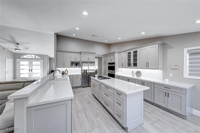 kitchen featuring gray cabinets, an island with sink, appliances with stainless steel finishes, and vaulted ceiling