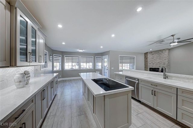 kitchen with ceiling fan, dishwasher, sink, black electric stovetop, and a kitchen island