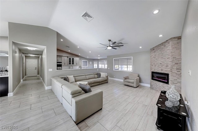 living room featuring ceiling fan, lofted ceiling, and a fireplace