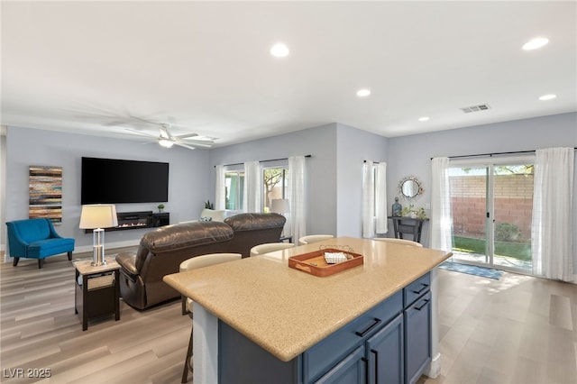 kitchen featuring a center island, light hardwood / wood-style floors, blue cabinets, and ceiling fan