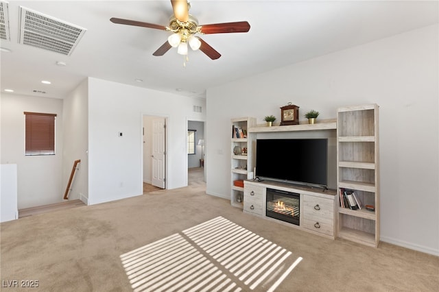 living room with ceiling fan, light colored carpet, and a fireplace