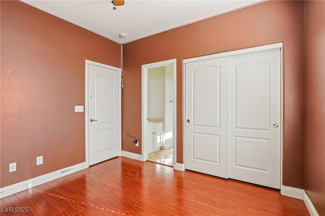 unfurnished bedroom featuring light hardwood / wood-style flooring, ensuite bath, and a closet