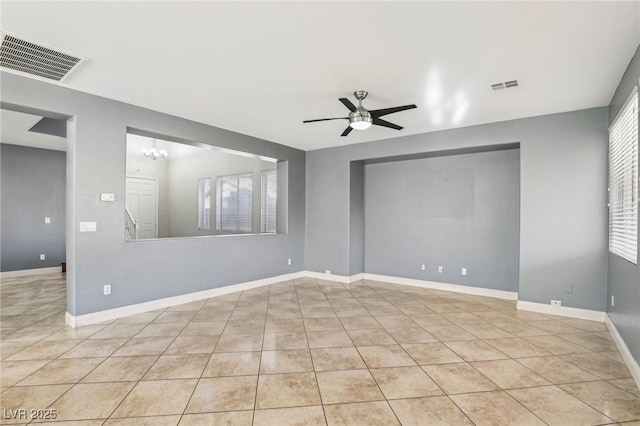 tiled empty room featuring ceiling fan with notable chandelier