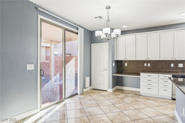 kitchen featuring decorative backsplash, pendant lighting, an inviting chandelier, dark stone countertops, and white cabinetry