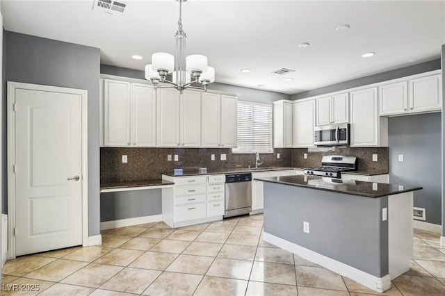 kitchen featuring white cabinetry, a center island, sink, pendant lighting, and appliances with stainless steel finishes