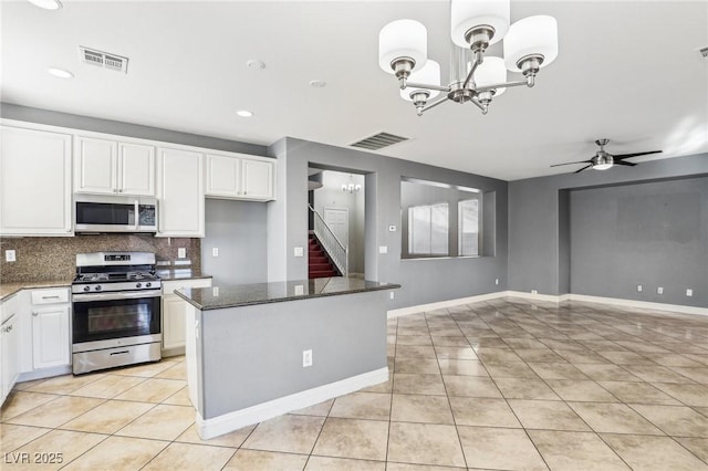 kitchen featuring white cabinets, ceiling fan with notable chandelier, dark stone countertops, light tile patterned flooring, and stainless steel appliances