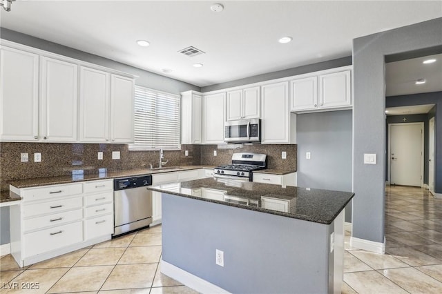 kitchen featuring a center island, sink, dark stone countertops, appliances with stainless steel finishes, and white cabinetry