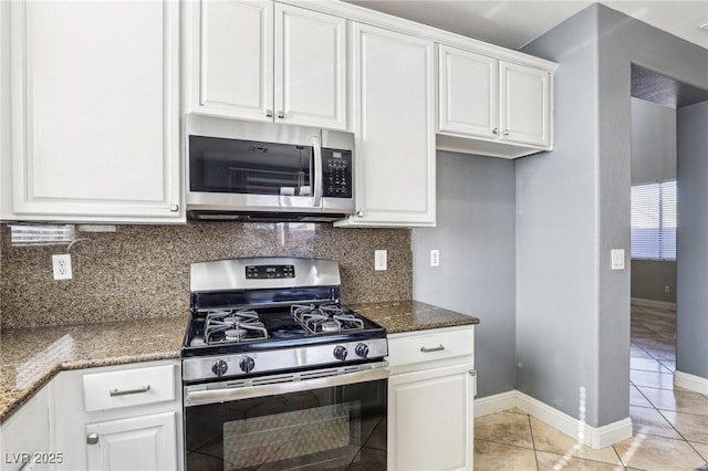 kitchen featuring backsplash, dark stone counters, light tile patterned floors, white cabinetry, and stainless steel appliances