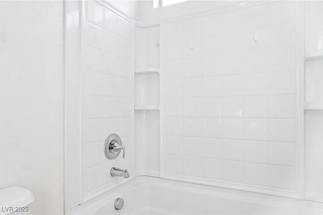 bathroom with tiled shower / bath combo and toilet