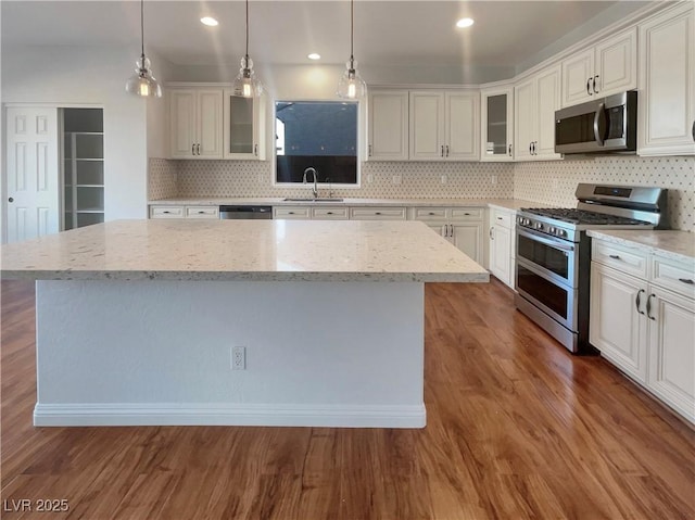 kitchen with appliances with stainless steel finishes, white cabinetry, and a kitchen island