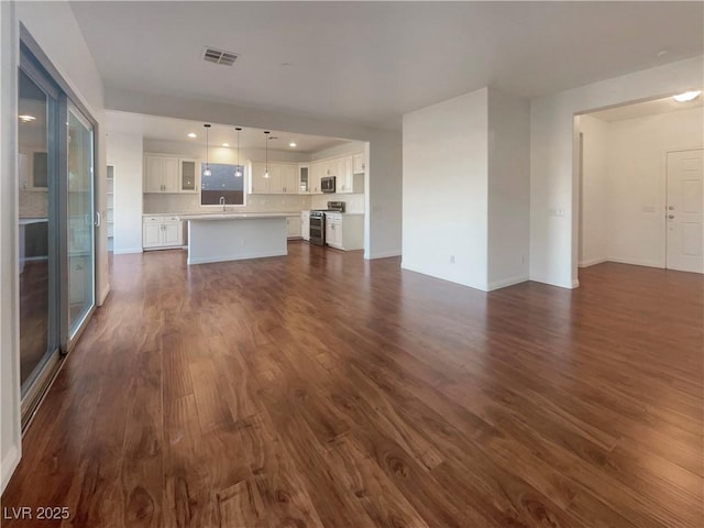 unfurnished living room featuring dark wood-type flooring and sink