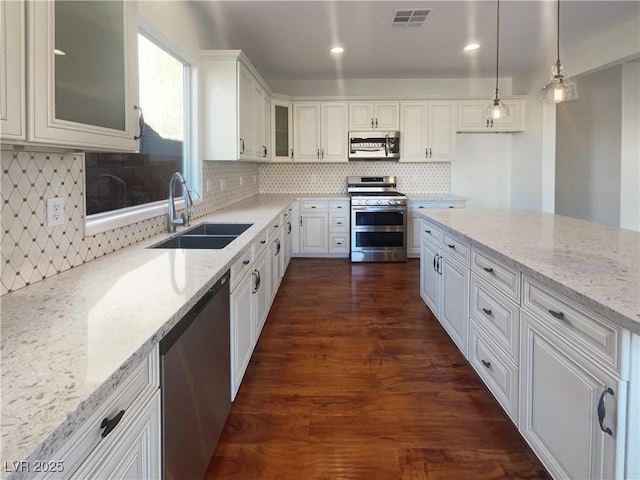 kitchen featuring pendant lighting, white cabinets, sink, appliances with stainless steel finishes, and light stone counters