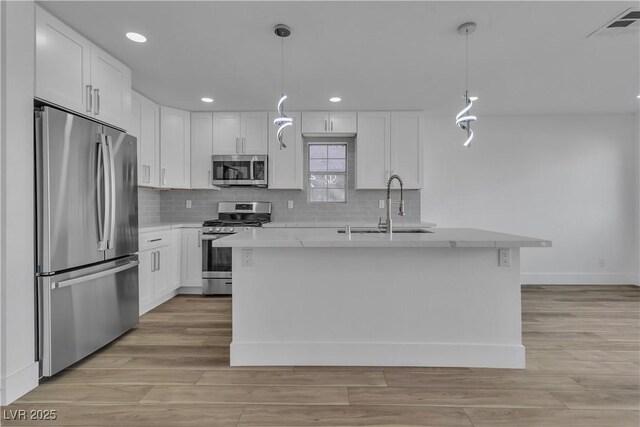 kitchen featuring white cabinetry, hanging light fixtures, stainless steel appliances, and sink