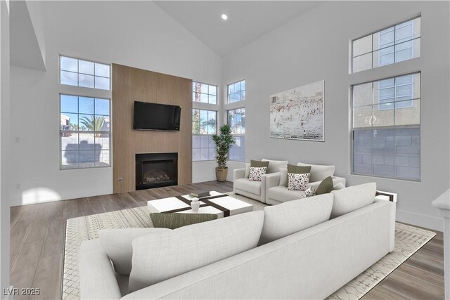 living room featuring a fireplace, a towering ceiling, and wood-type flooring