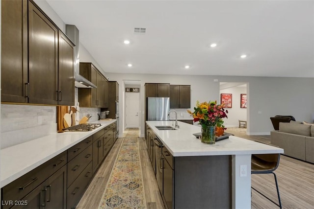 kitchen featuring a kitchen breakfast bar, sink, light hardwood / wood-style flooring, tasteful backsplash, and stainless steel appliances