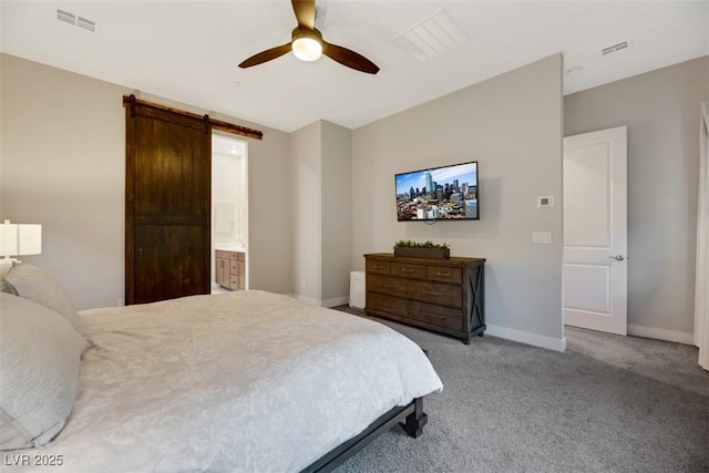 bedroom featuring light carpet, a barn door, ceiling fan, and connected bathroom