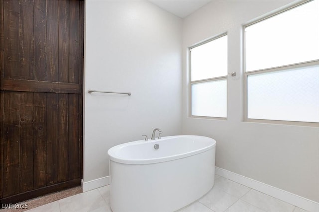 bathroom with tile patterned floors, a bathtub, and a wealth of natural light