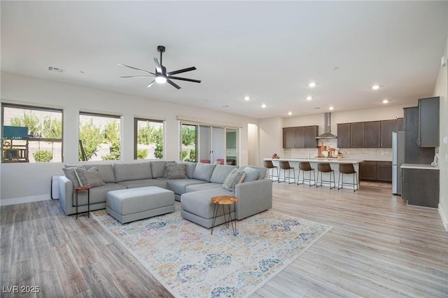 living room with light hardwood / wood-style floors and ceiling fan