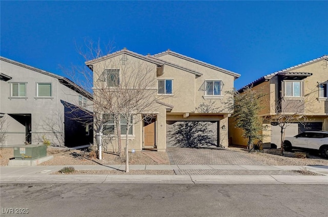 traditional home with an attached garage, decorative driveway, and stucco siding