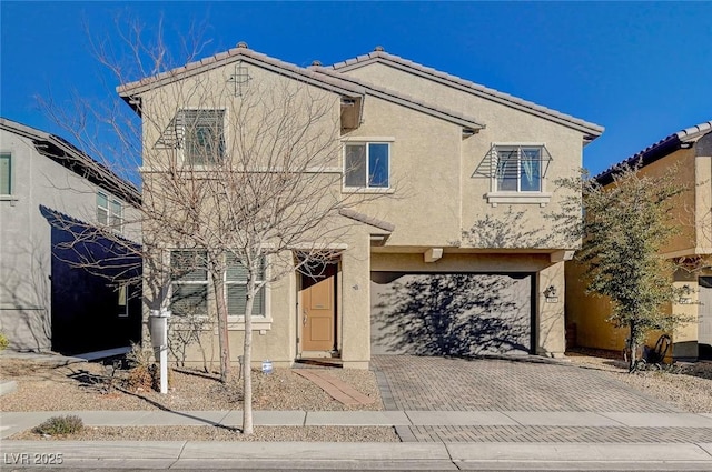 view of front of home featuring a garage, decorative driveway, a tiled roof, and stucco siding