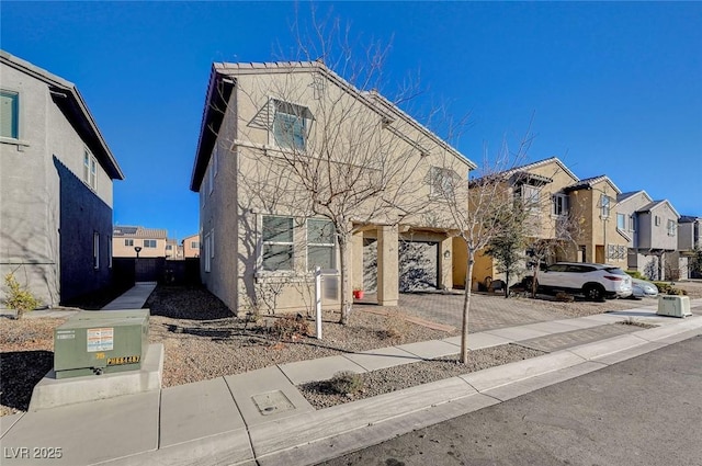 view of front of property with decorative driveway, a residential view, and stucco siding