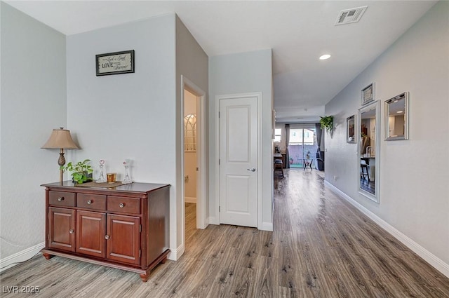 hall with light wood-style floors, baseboards, and visible vents