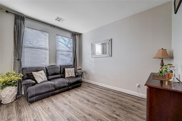 living area featuring wood finished floors, visible vents, and baseboards