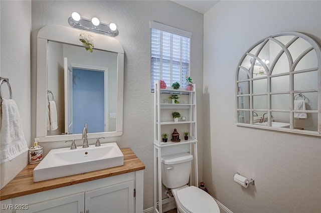 bathroom with a textured wall, vanity, and toilet