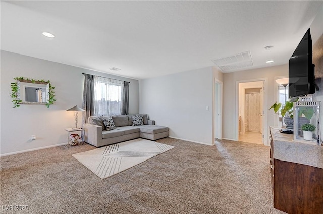 living area featuring baseboards, visible vents, and light colored carpet