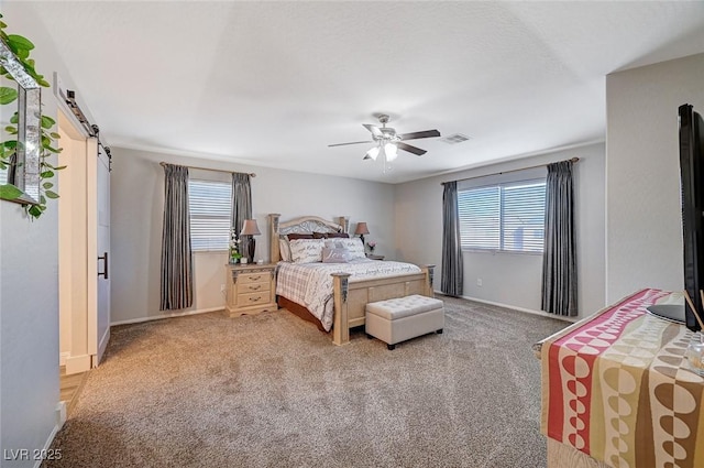 carpeted bedroom with visible vents, ceiling fan, baseboards, and a barn door