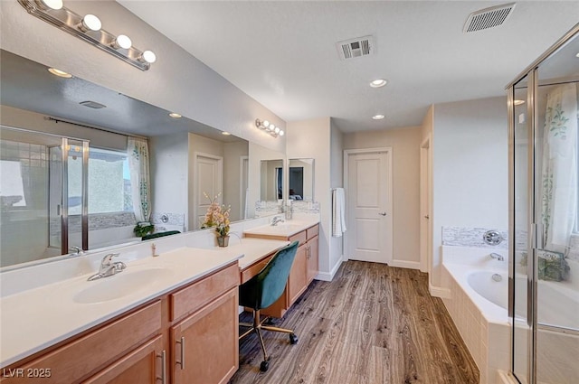 bathroom with vanity, wood finished floors, visible vents, and a shower stall