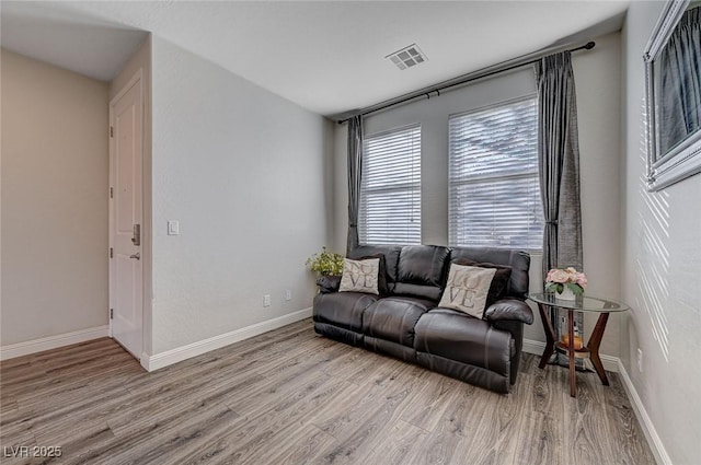 living area featuring baseboards, visible vents, and light wood finished floors