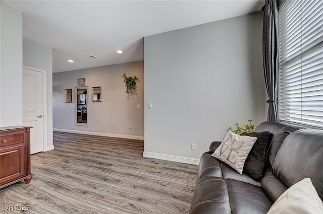 living area featuring light wood-style flooring, baseboards, and recessed lighting