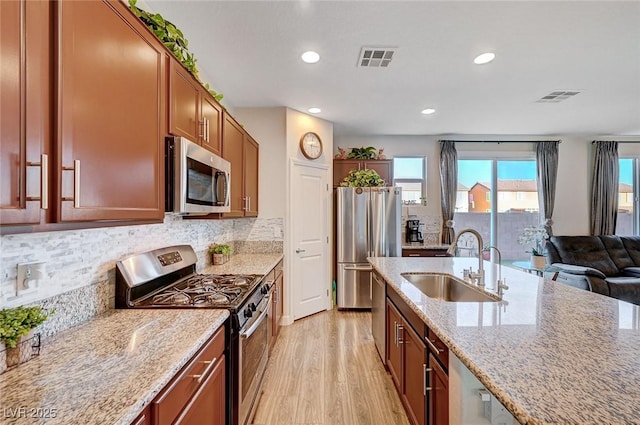 kitchen with stainless steel appliances, a sink, visible vents, and light stone countertops