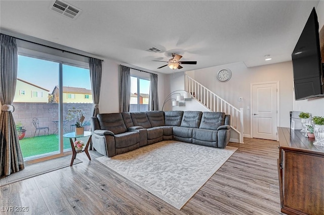 living area featuring light wood-type flooring, visible vents, and stairway