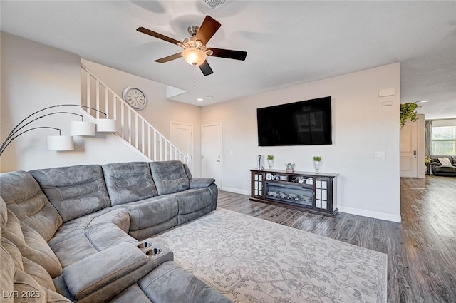 living room with a ceiling fan, stairs, baseboards, and wood finished floors