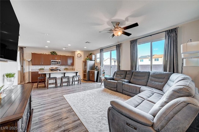 living room featuring ceiling fan, visible vents, light wood-style flooring, and recessed lighting