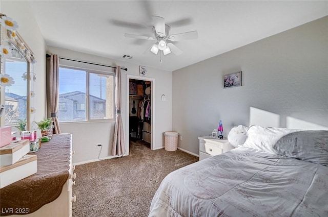 bedroom with baseboards, visible vents, a ceiling fan, a spacious closet, and dark colored carpet