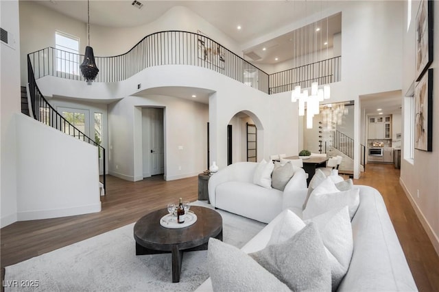 living room with a chandelier, a high ceiling, and hardwood / wood-style flooring