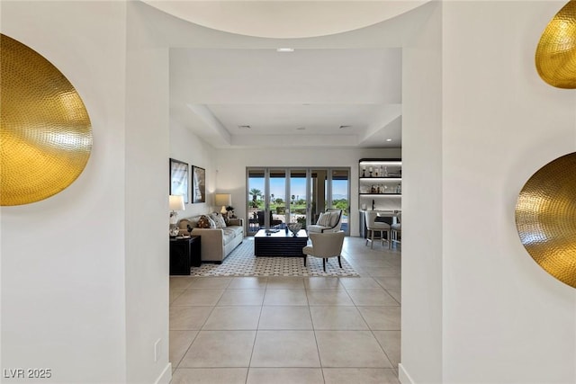 living room with a tray ceiling and light tile patterned floors