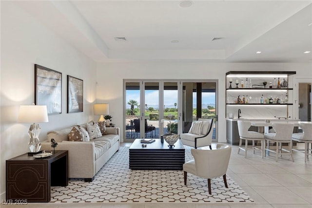 living room with light tile patterned flooring, a raised ceiling, and bar