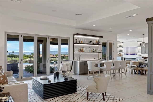 tiled living room with bar and a tray ceiling