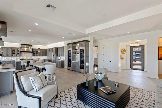 living room with a tray ceiling and light tile patterned flooring