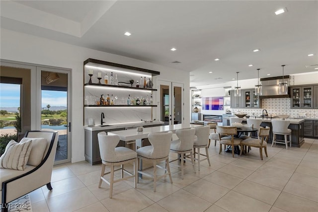 bar with french doors, sink, decorative backsplash, light tile patterned floors, and decorative light fixtures