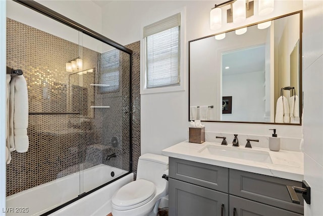 full bathroom with vanity, bath / shower combo with glass door, and toilet