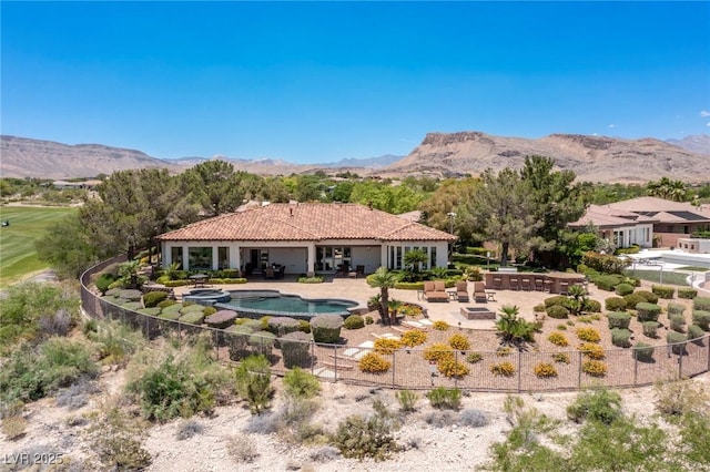 back of property featuring a mountain view, an in ground hot tub, and a patio